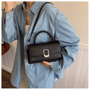 Detail view of black vintage handbag with silver buckle and fine grain leather texture