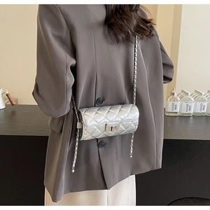 Close-up of silver quilted cylinder bag with metal chain strap worn as a crossbody