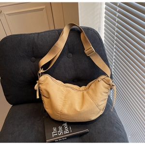 Detail of khaki crescent crossbody bag texture and wide strap on corduroy chair