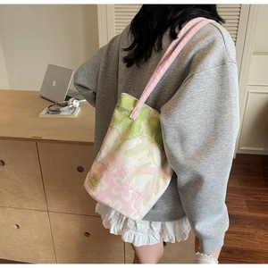 Detail of canvas bucket bag with floral jacquard pattern and pink shoulder strap