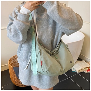Detail of mint green nylon hobo bag with adjustable wide strap and side red label