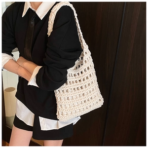 Close-up of minimalist cream knit tote bag with mesh pattern on female model