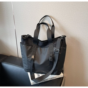 Detail view of black nylon multi-pocket tote bag with buckle straps and top handles