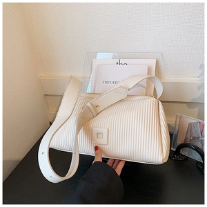 Close-up of vertical pleated texture and leather buckle on a cream shoulder bag