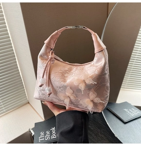 Détail du sac brodé rose avec papillons 3D et pompon de perles sur la fermeture éclair
