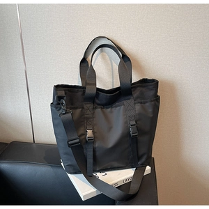 Close-up of black nylon tote bag with utility buckles and adjustable shoulder strap