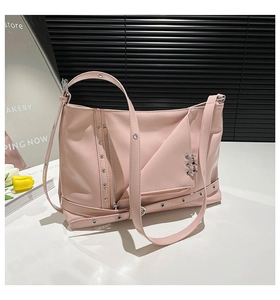 Close-up of pink PU leather crossbody bag featuring silver metal rivets and flap details