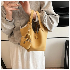 Detail view of mustard yellow pebbled leather bucket bag with matching small coin pouch