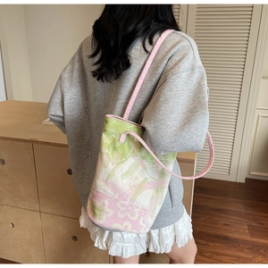 Detail of floral canvas bucket bag showing jacquard print and shoulder strap on model