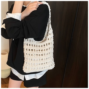 Detail of hollow knit mesh texture and geometric woven pattern on the cream tote bag