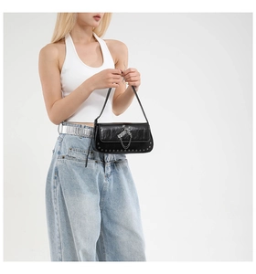 Detail of black faux leather bag featuring silver cross charms, chains and metal rivets