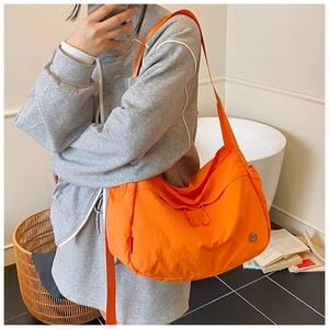 Vibrant orange nylon tote bag detail with wide strap and zip pulls in a mirror selfie