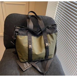 Detail of olive green nylon tote bag with dual handles and adjustable crossbody strap