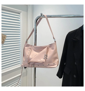Pink glossy patent leather crossbody bag with silver metal eyelets and buckled strap detail