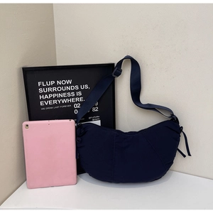 Detail of navy nylon hobo bag showing adjustable strap and minimalist crescent shape