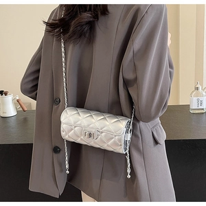 Detail of silver quilted chain bag worn by model over a grey blazer for a modern style
