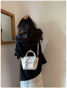 Rear view of model wearing white PU leather trapezoid handbag with gold hardware details