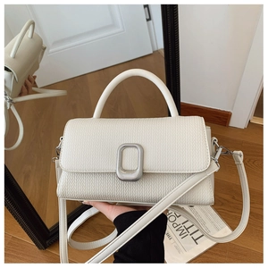 Detailed macro view of cream-colored woven texture and silver buckle on this small handbag