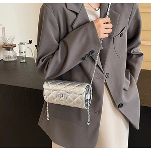 Detail of silver quilted cylinder bag with metal chain strap and turn-lock closure