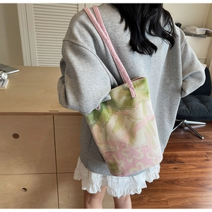 Detail shot of the floral jacquard canvas bucket bag with pink strap and brand tag