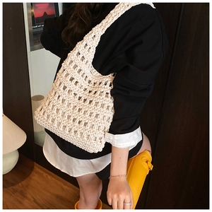Detail of hand-crocheted hollow mesh shoulder bag with wide woven strap on model