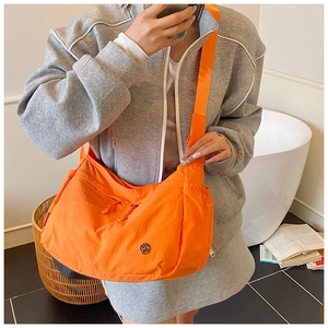 Mirror selfie showing the bright orange nylon crossbody bag with wide adjustable shoulder strap