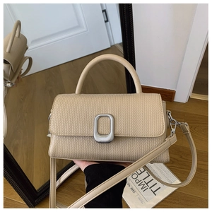 Detail of beige crossbody bag with textured leather and silver buckle shown in mirror