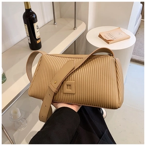 Detail of khaki pleated pillow bag with a wide shoulder strap and elegant gold studs