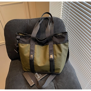 Close-up of olive green and black large tote bag with buckle straps on a modern chair