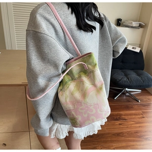 Detail of canvas bucket bag with pink and green floral print and slim shoulder strap