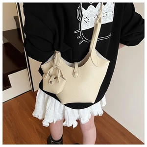 Detail of beige bucket bag in lychee leather texture with matching mini charm pouch