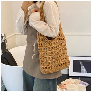 Detailed close-up of a handmade hollow crochet tote bag with a white drawstring inner pouch