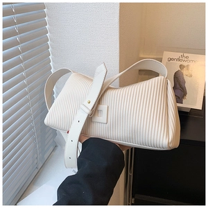 Detail view of cream white pleated shoulder bag with square buckle and adjustable strap