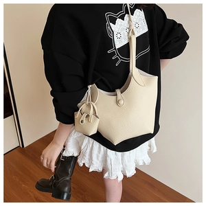 Detail of a creamy white litchi grain leather bucket bag with a mini matching pouch charm