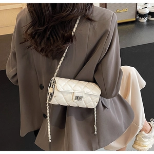 Chic white quilted barrel bag with chain strap worn with a casual brown blazer