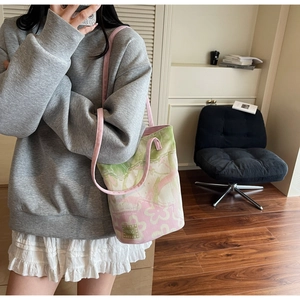 Detail shot of jacquard floral canvas bucket bag with pink shoulder strap and side logo tag