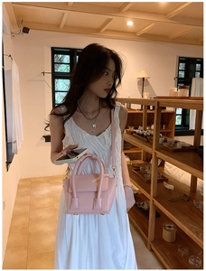 Detailed view of pink leather crossbody bag with circular handle and gold metal studs