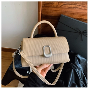 Detail of woven texture and silver square lock on beige structured crossbody handbag