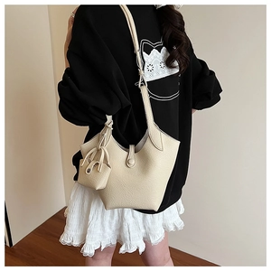 Detail of minimalist cream leather bucket bag with matching mini pouch and button closure