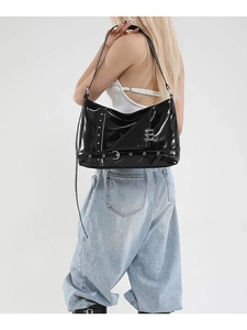 Chic black glossy punk tote bag with silver studs and metal buckles on a fashion model