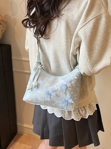 Sac hobo bleu clair brodé avec papillons 3D porté à l'épaule par un mannequin