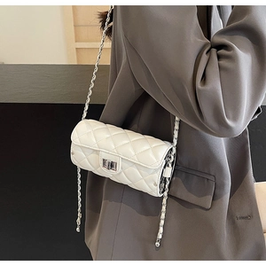 Detailed side view of white quilted cylinder bag with silver chain strap on model