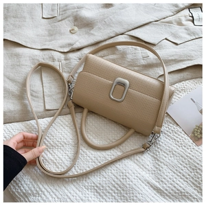 Detail of beige lychee leather crossbody bag with silver square metal lock and handle