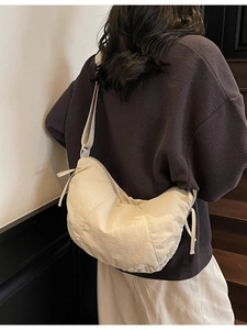 Minimalist cream-white dumpling shoulder bag with side bow detail on female model