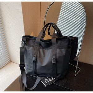 Close-up of black waterproof nylon tote bag showing buckled straps and texture