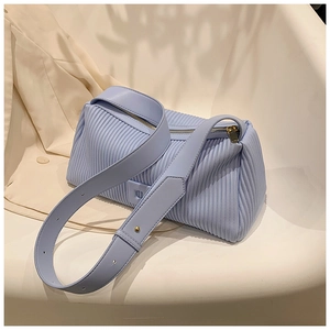 Detail of light blue accordion pleat handbag with golden zipper on a white chair