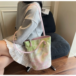 Detailed shot of a floral canvas bucket bag with pink straps worn on the shoulder