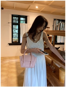 Detailed side view of pink faux leather tote bag with reinforced handles in a cozy setting