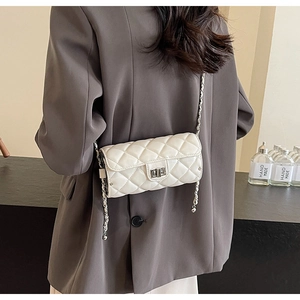 Detail of white quilted rhombus chain bag featuring a silver metal twist lock closure