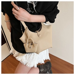 Detail view of beige bucket bag showing high-quality lychee texture and mini charm